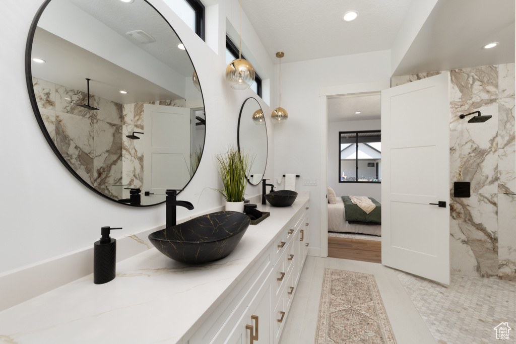 Full bath with double vanity, recessed lighting, a marble finish shower, and connected bathroom