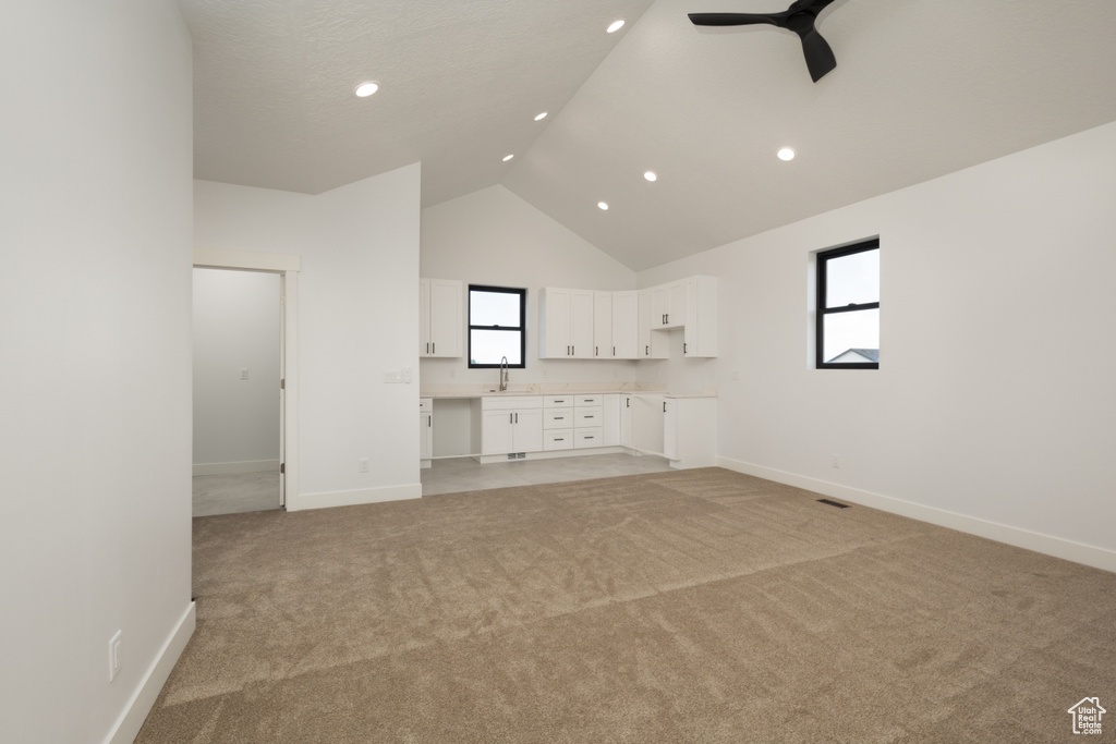 Unfurnished living room featuring high vaulted ceiling, light carpet, a ceiling fan, baseboards, and recessed lighting