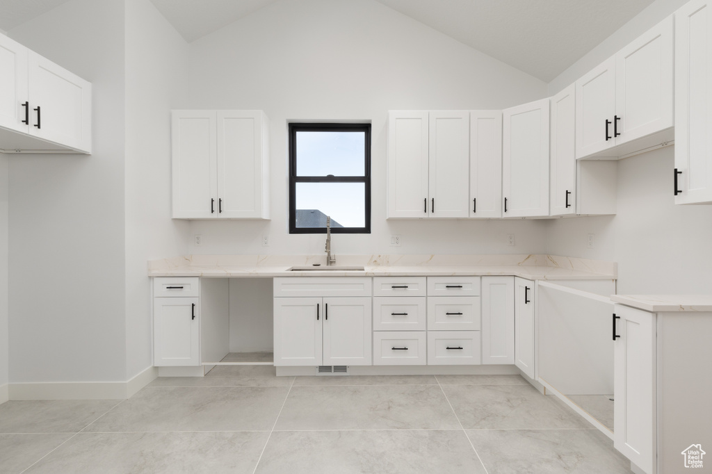 Kitchen with a sink, white cabinetry, light countertops, and high vaulted ceiling