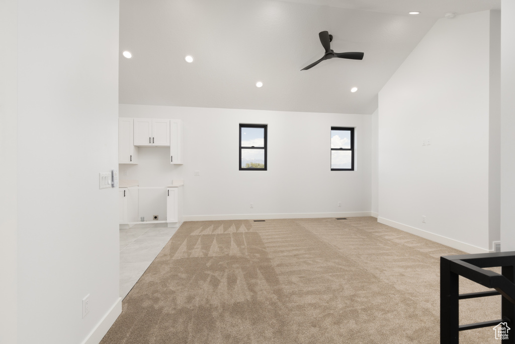 Unfurnished living room with a ceiling fan, light carpet, recessed lighting, baseboards, and high vaulted ceiling