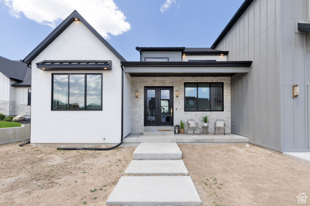 View of front of house with french doors, a porch, board and batten siding, stucco siding, and a standing seam roof