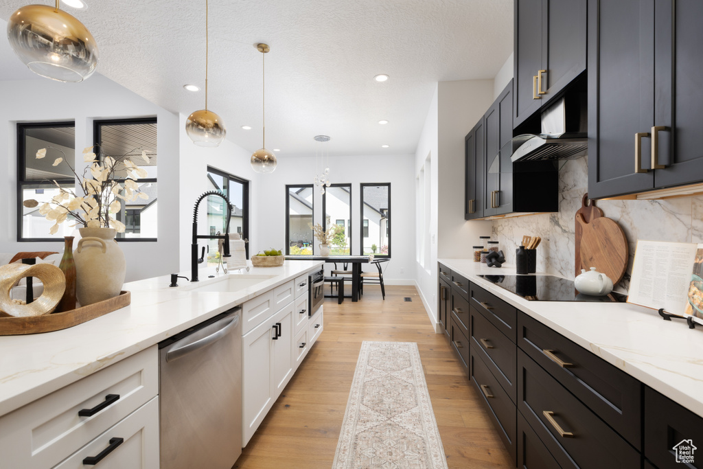 Kitchen with dishwasher, a sink, decorative backsplash, pendant lighting, and light wood-style floors