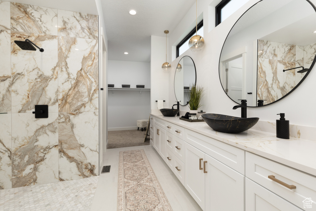 Full bath with double vanity, a marble finish shower, recessed lighting, and a walk in closet