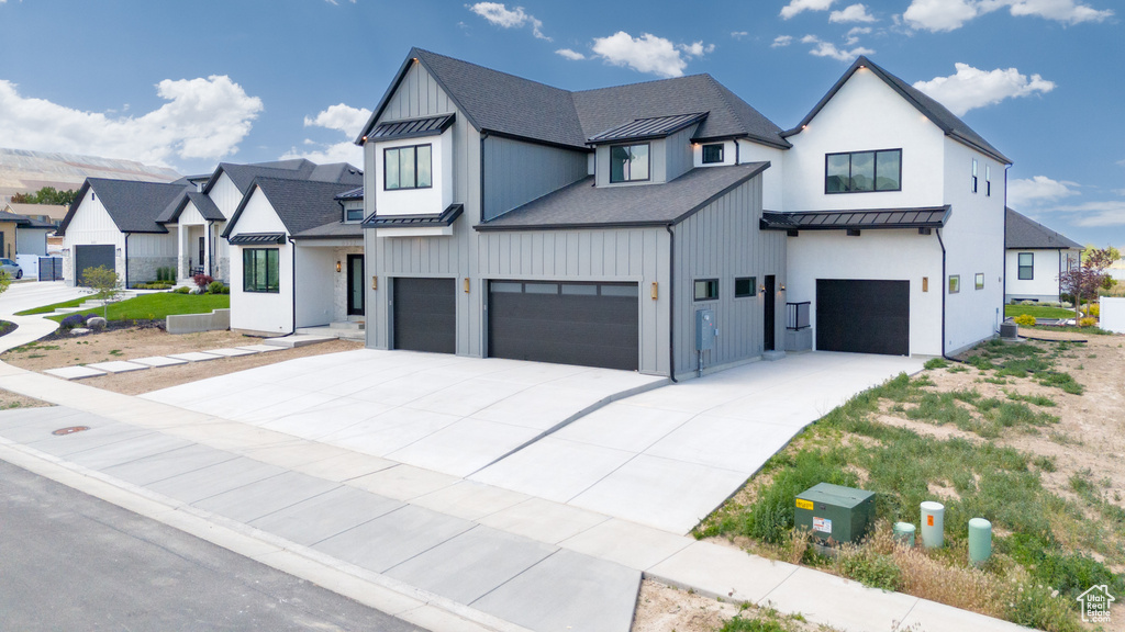 Modern farmhouse style home featuring a standing seam roof, an attached garage, metal roof, roof with shingles, and concrete driveway