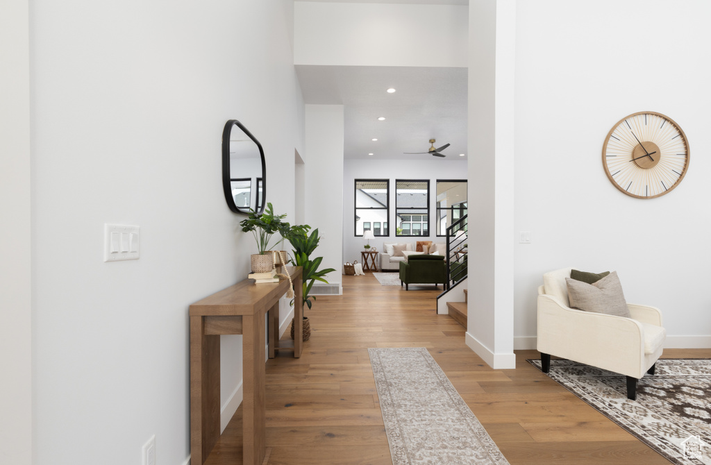 Hall with light wood-style flooring, baseboards, stairs, and recessed lighting