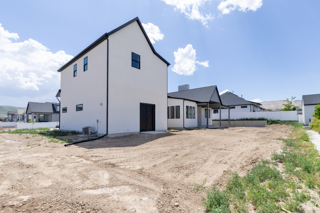 Back of property featuring stucco siding and central AC