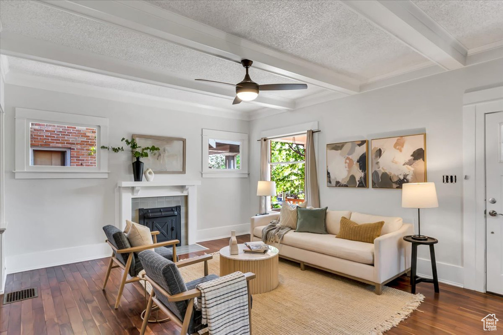 Living area with a textured ceiling, a fireplace with flush hearth, beamed ceiling, hardwood / wood-style floors, and baseboards