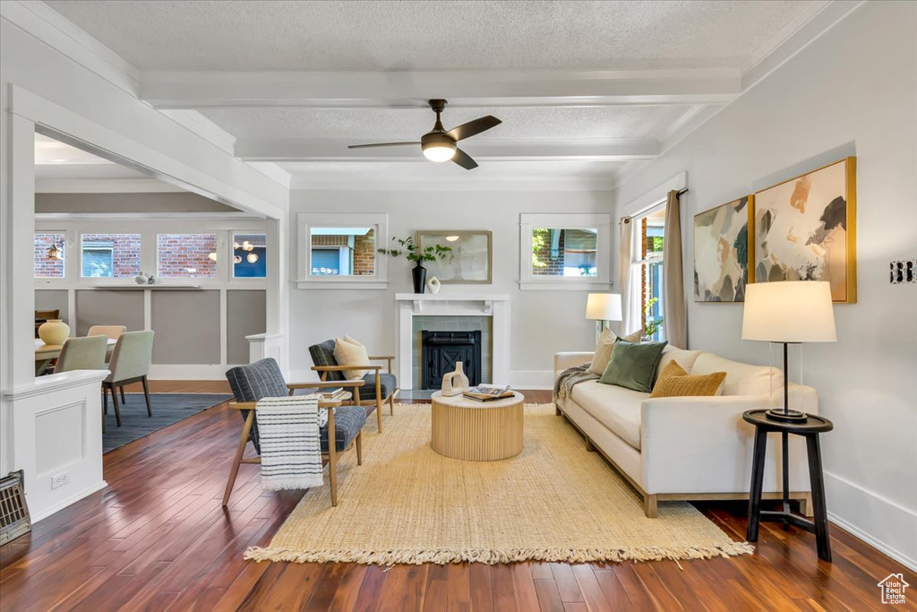 Living area with wood-type flooring, beam ceiling, a fireplace with flush hearth, baseboards, and ceiling fan