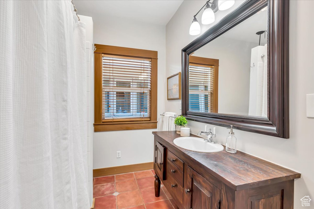 Full bath with vanity, tile patterned floors, and baseboards