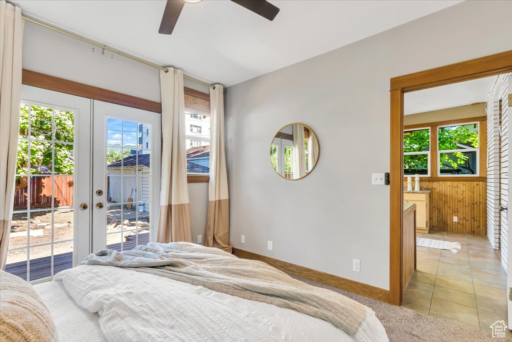 Bedroom featuring access to outside, french doors, multiple windows, wooden walls, and baseboards