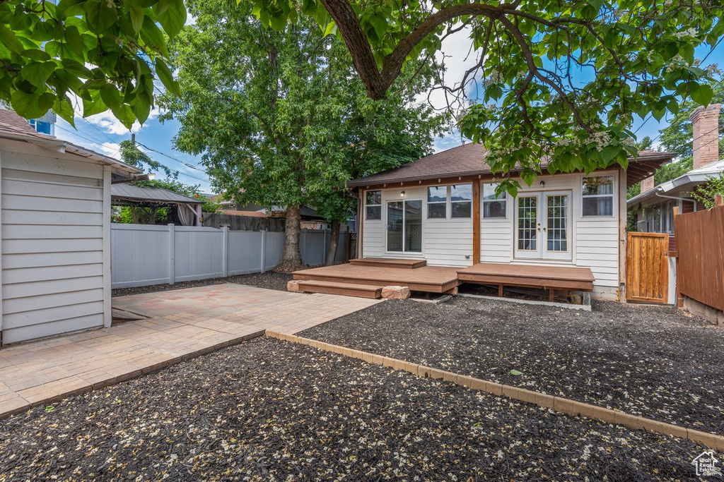 Back of property with french doors, a fenced backyard, a deck, and a gazebo