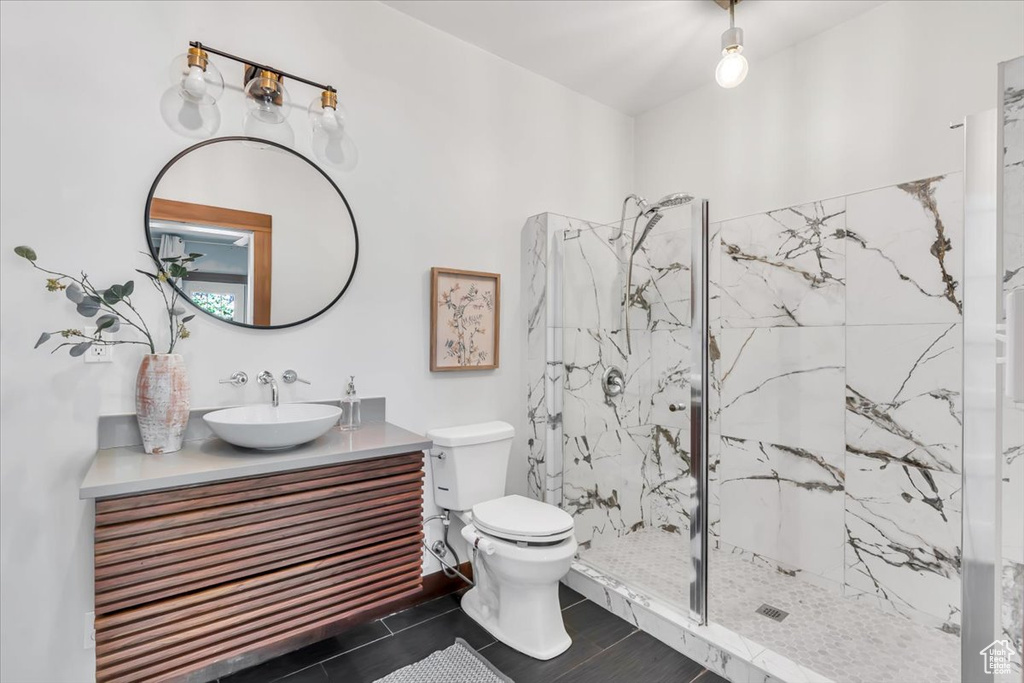 Full bath featuring vanity, a marble finish shower, and toilet