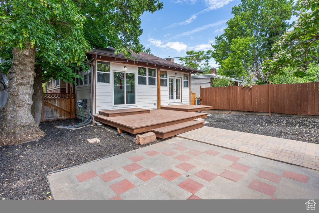 Back of property with a deck, a fenced backyard, french doors, and a patio