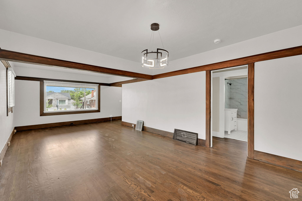 Spare room featuring a chandelier, wood finished floors, baseboards, and a smoke detector