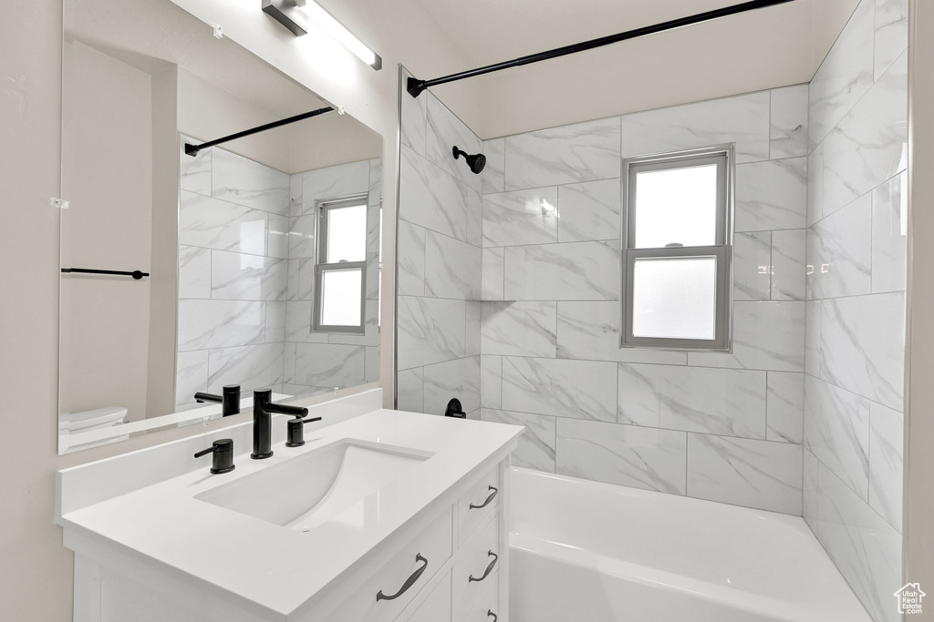 Full bathroom with vanity, tub / shower combination, plenty of natural light, and toilet