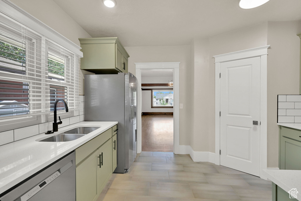 Kitchen with green cabinets, appliances with stainless steel finishes, a sink, and plenty of natural light