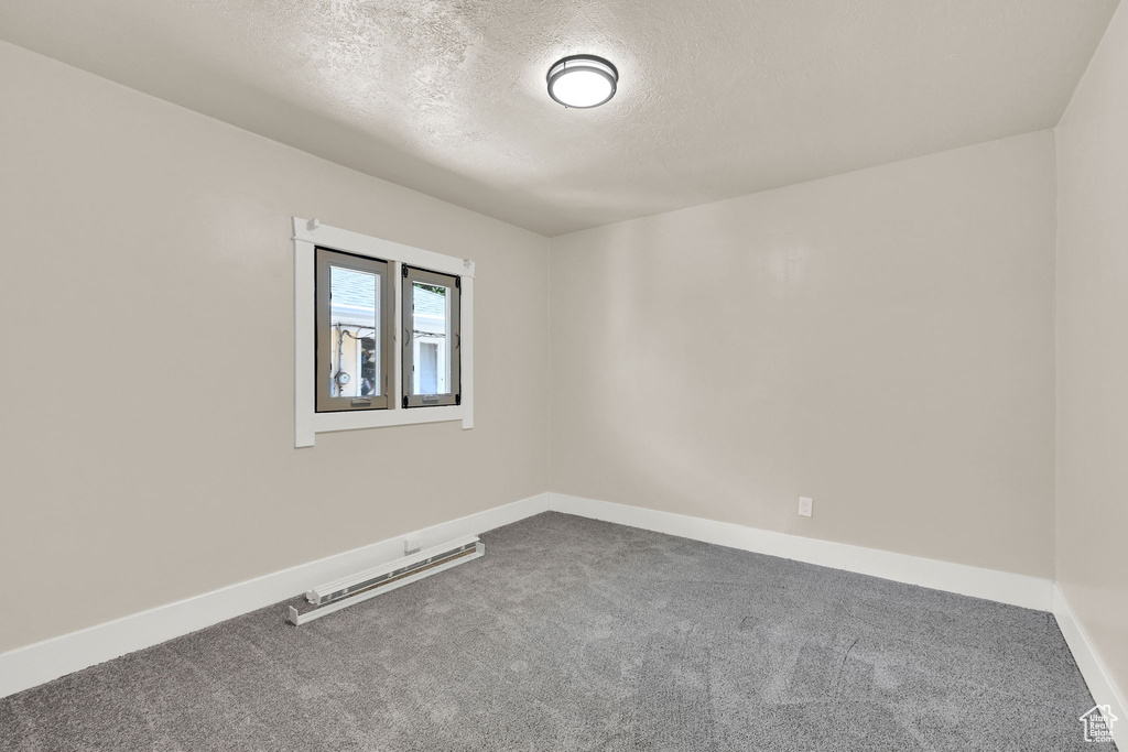 Spare room with carpet, a textured ceiling, and baseboards
