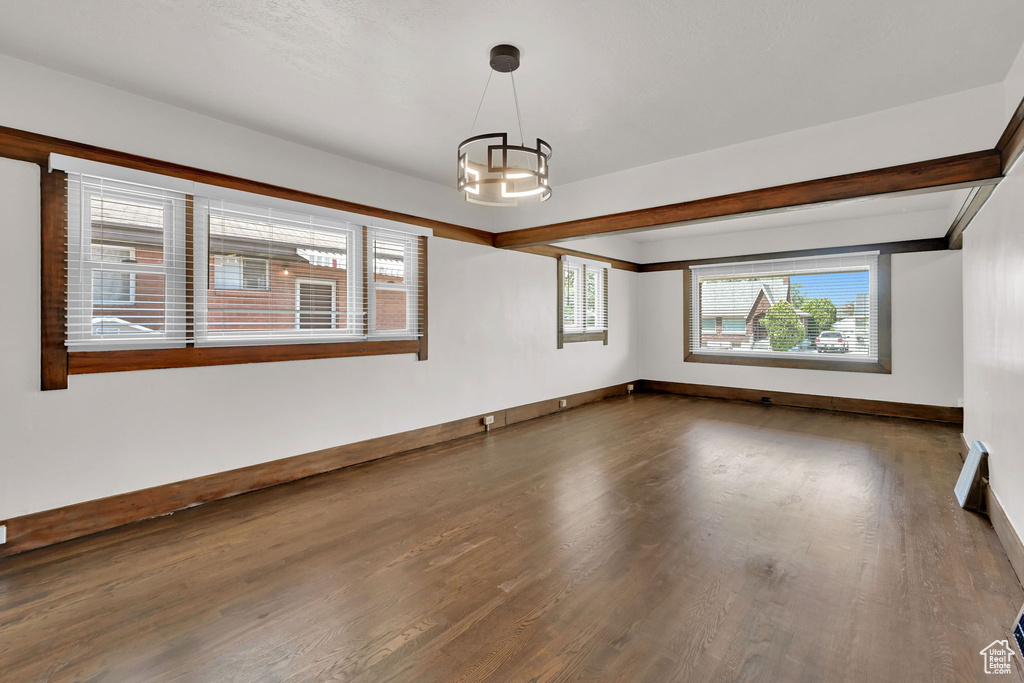 Unfurnished room featuring wood finished floors, a chandelier, and baseboards