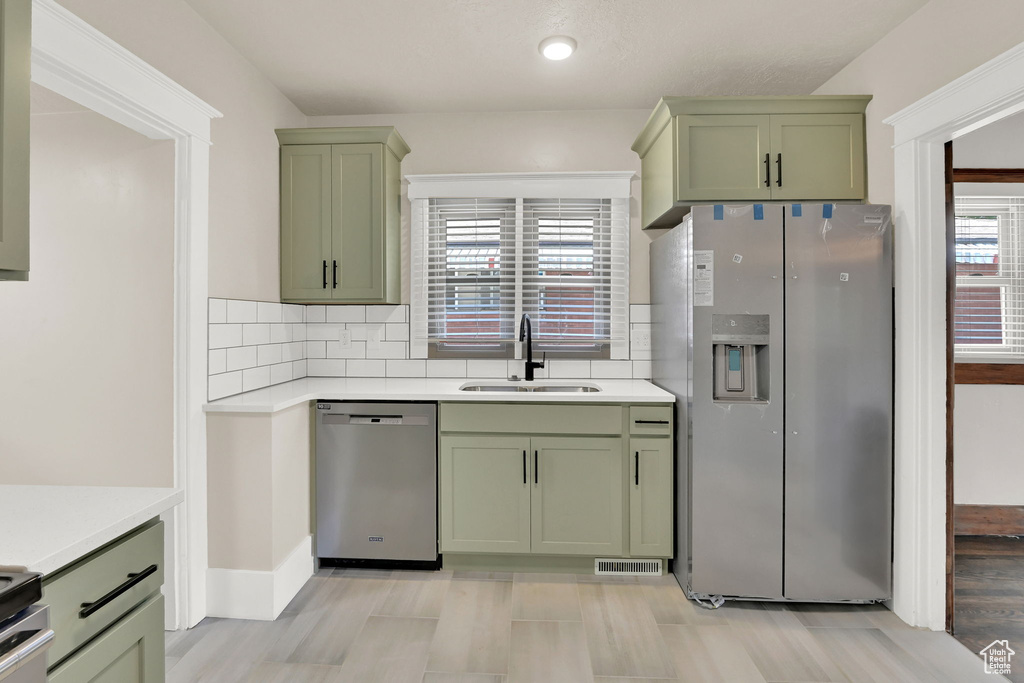 Kitchen featuring green cabinets, stainless steel appliances, a sink, light countertops, and recessed lighting