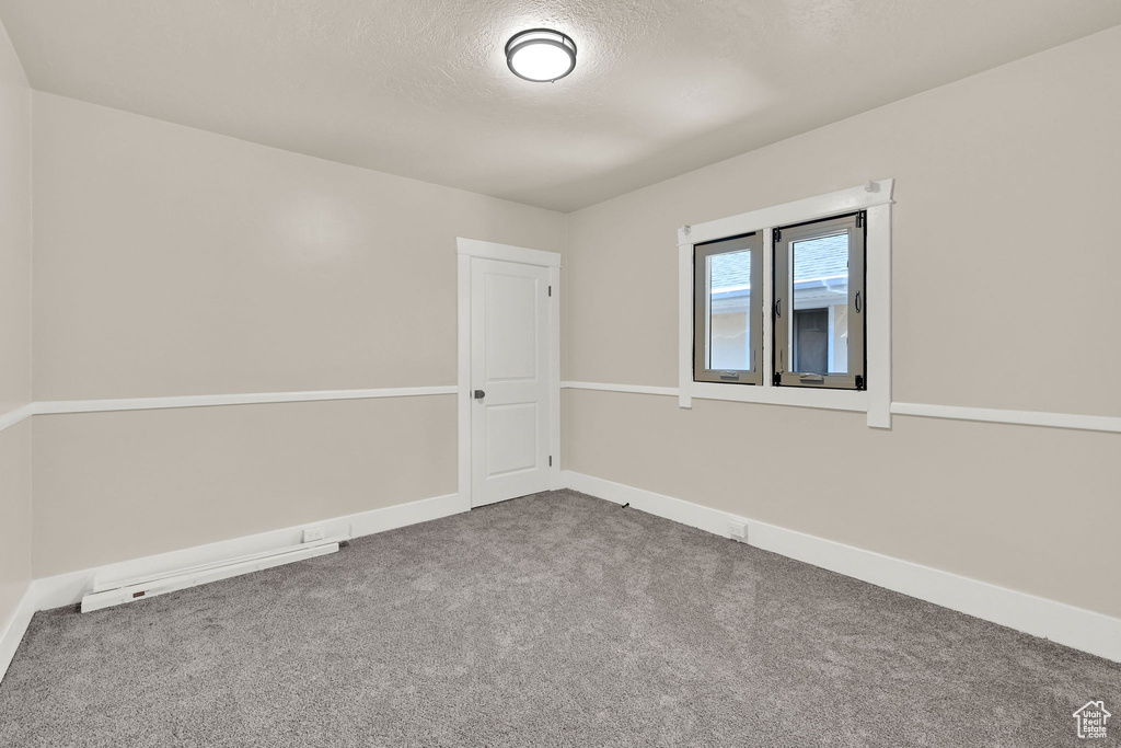 Empty room with carpet floors, a textured ceiling, and baseboards
