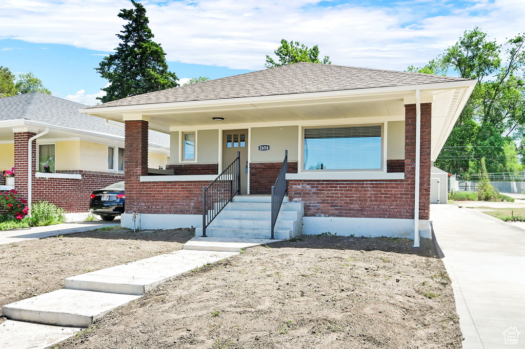 Bungalow featuring brick siding, a porch, and a shingled roof