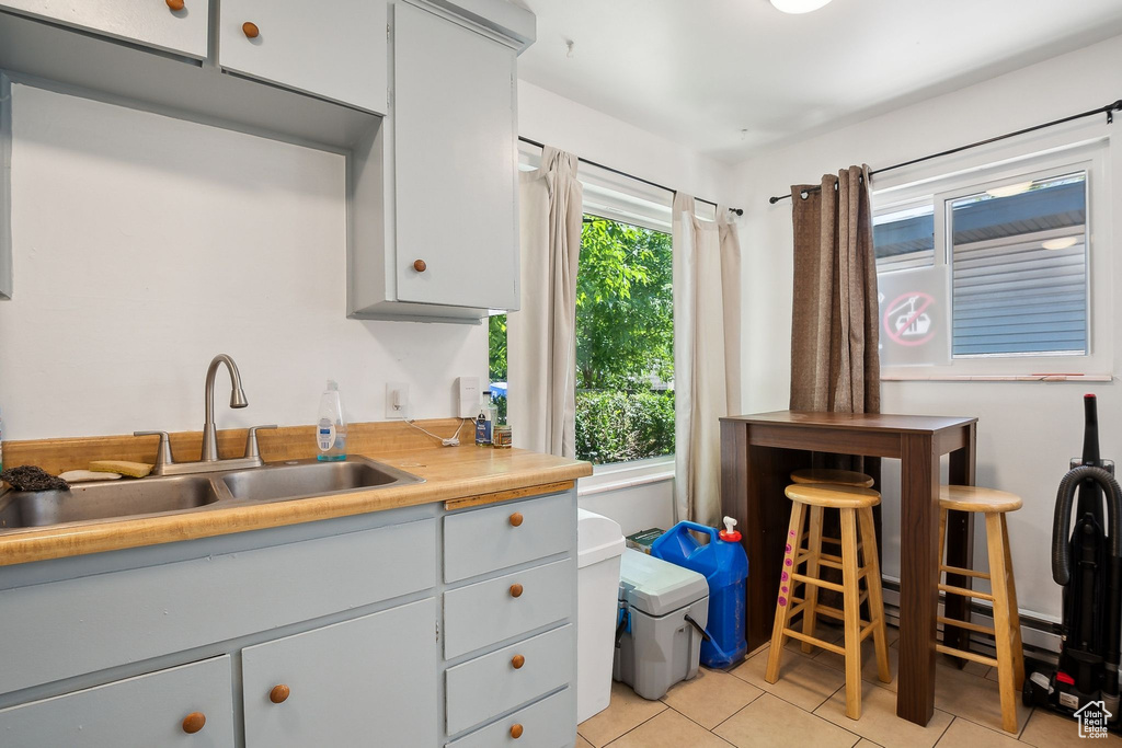 Kitchen with a sink, light tile patterned flooring, light countertops, and gray cabinets