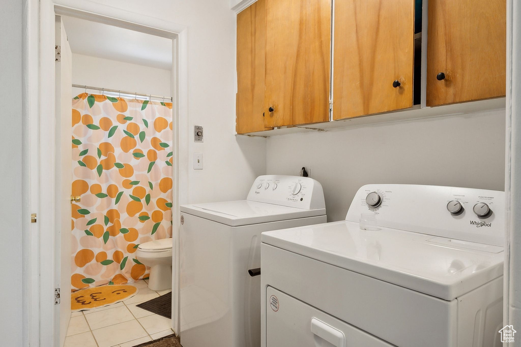 Laundry area with washer and dryer, tile patterned floors, and cabinet space