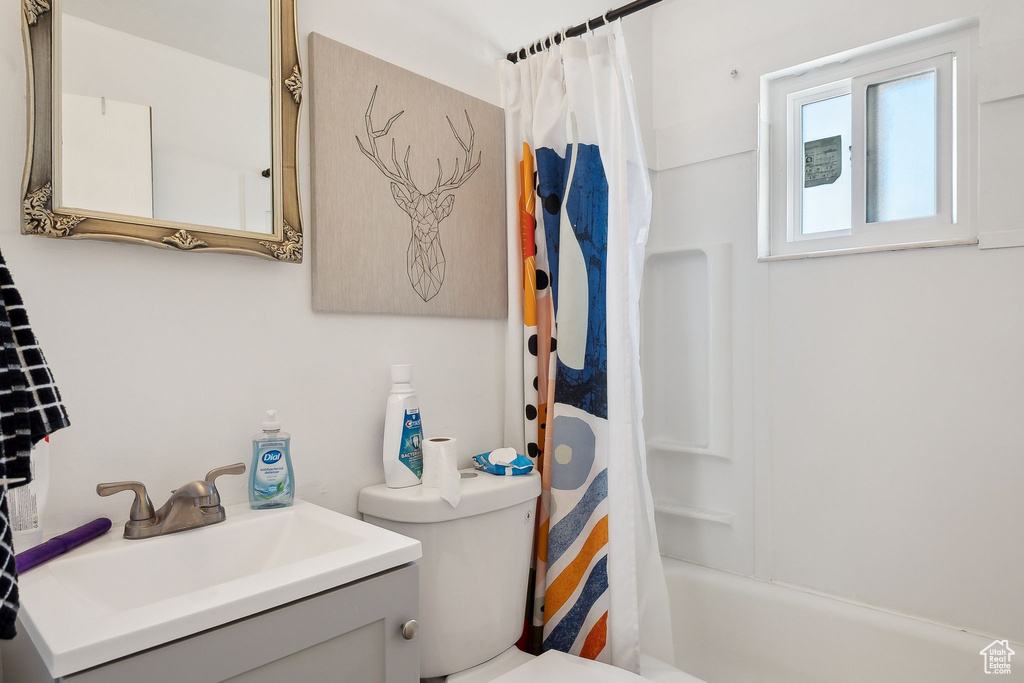 Bathroom featuring toilet, vanity, and shower / bath combo
