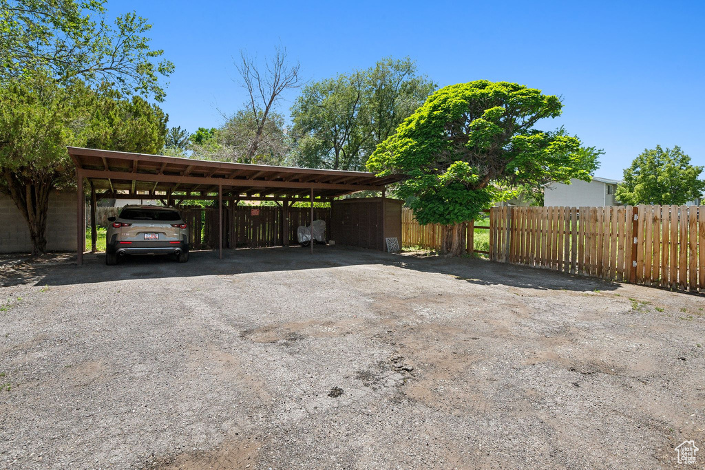 View of parking featuring asphalt driveway and a carport