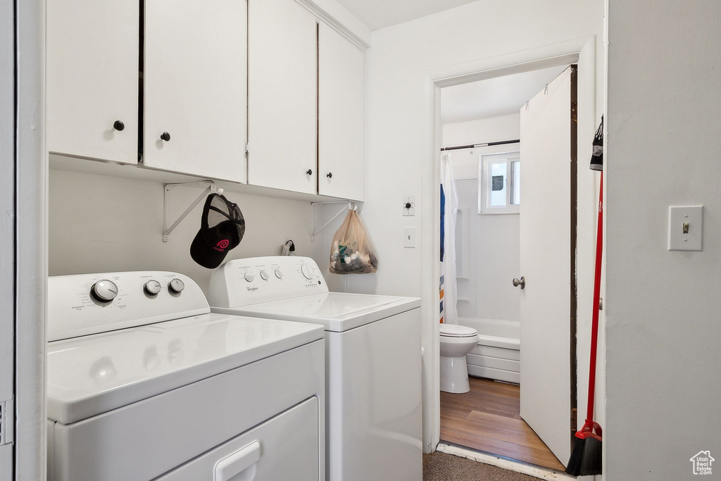 Laundry room featuring washer and clothes dryer, cabinet space, and light wood-style floors