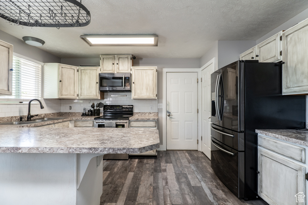 Kitchen featuring appliances with stainless steel finishes, a sink, dark wood-style floors, tasteful backsplash, and a textured ceiling