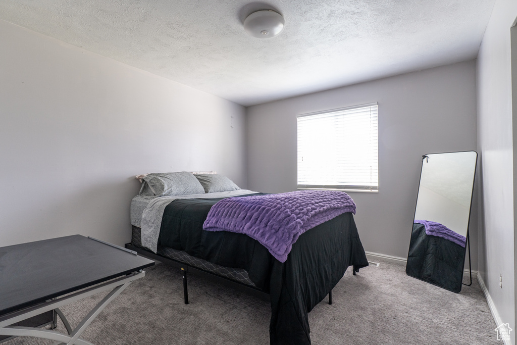 Carpeted bedroom featuring a textured ceiling and baseboards