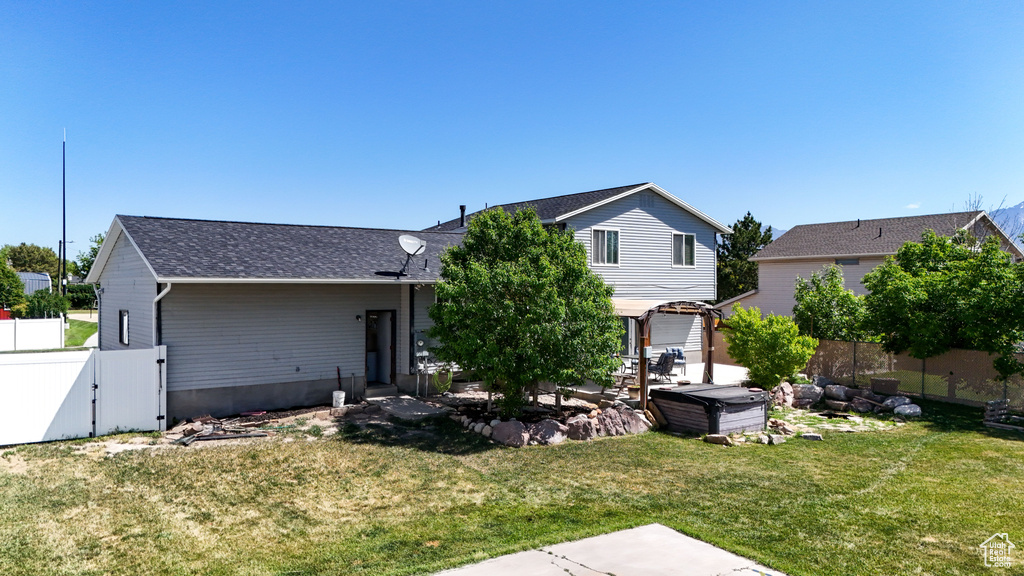 Rear view of property featuring a patio, a gate, and a shingled roof
