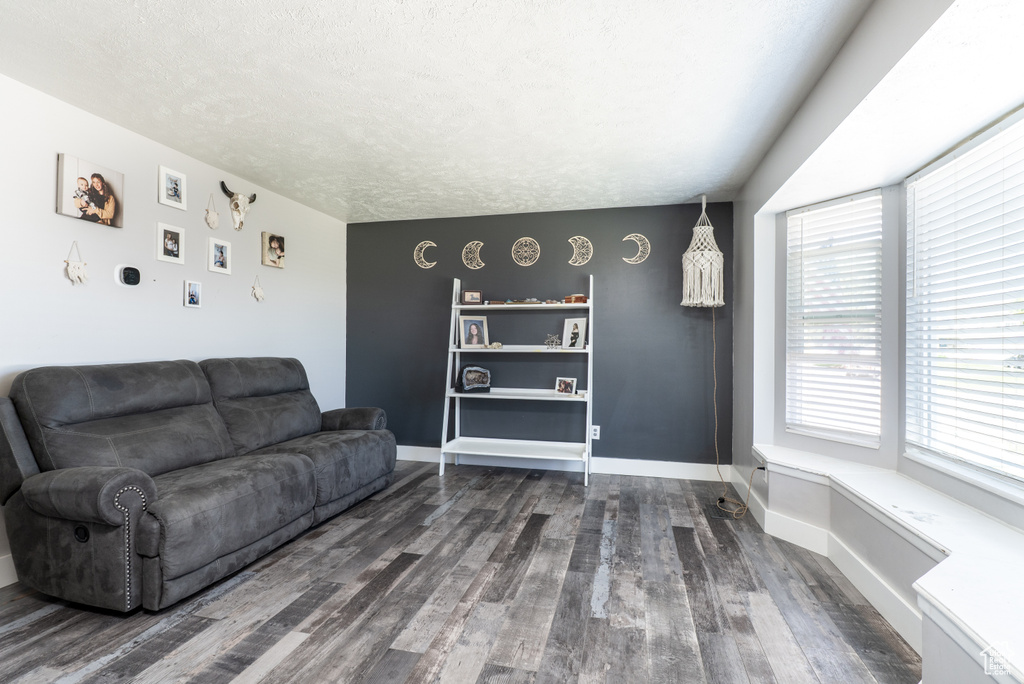 Living area with wood finished floors, baseboards, and a textured ceiling