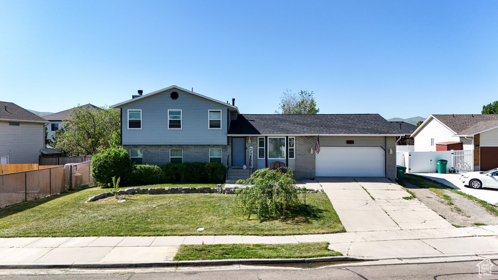 Split level home featuring a garage, concrete driveway, and brick siding
