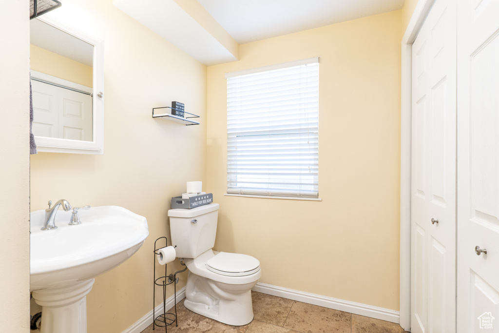 Bathroom featuring toilet, baseboards, a closet, and tile patterned flooring