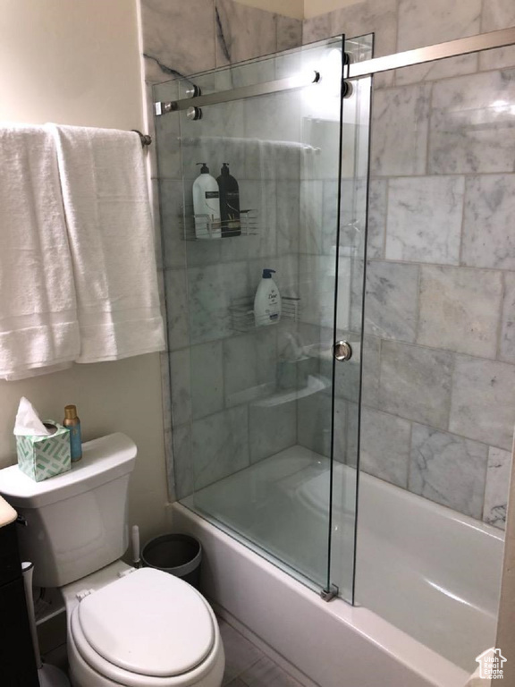 Full bath featuring shower / bath combination with glass door, toilet, and vanity
