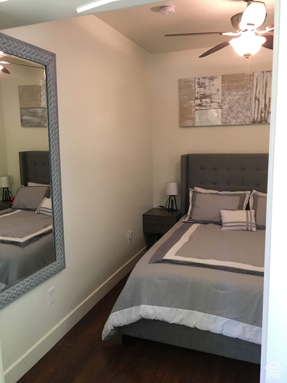 Bedroom with dark wood finished floors, baseboards, and ceiling fan