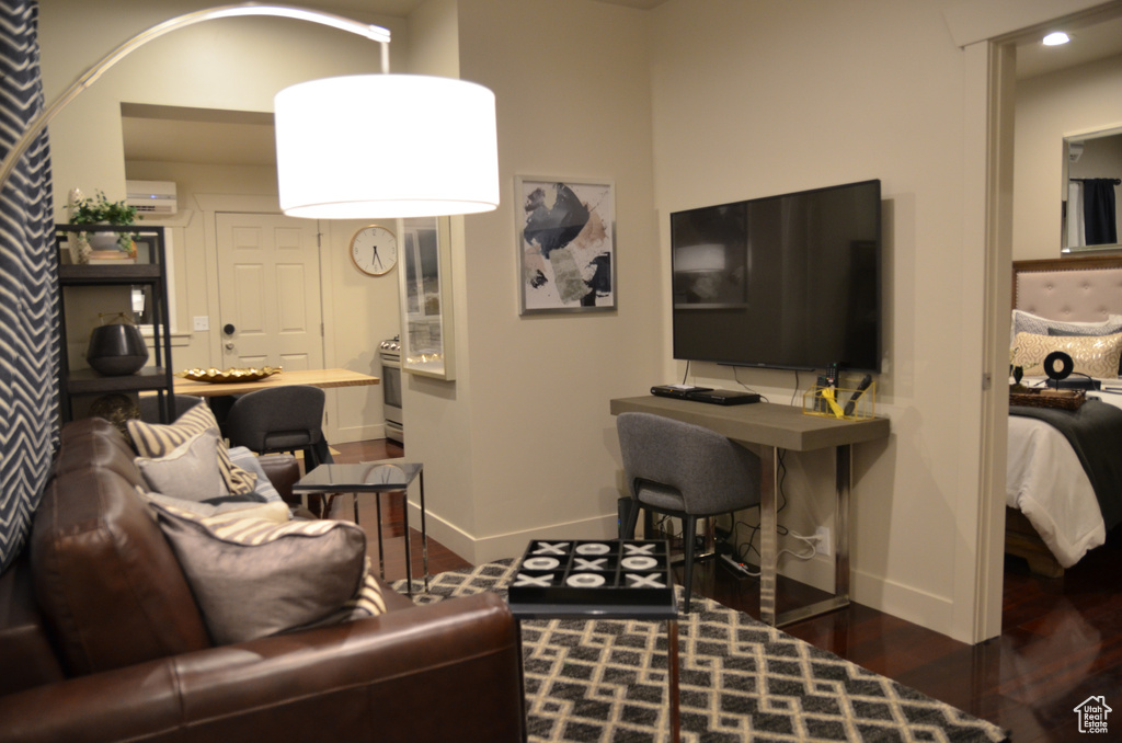 Living room featuring baseboards, wood finished floors, and an AC wall unit