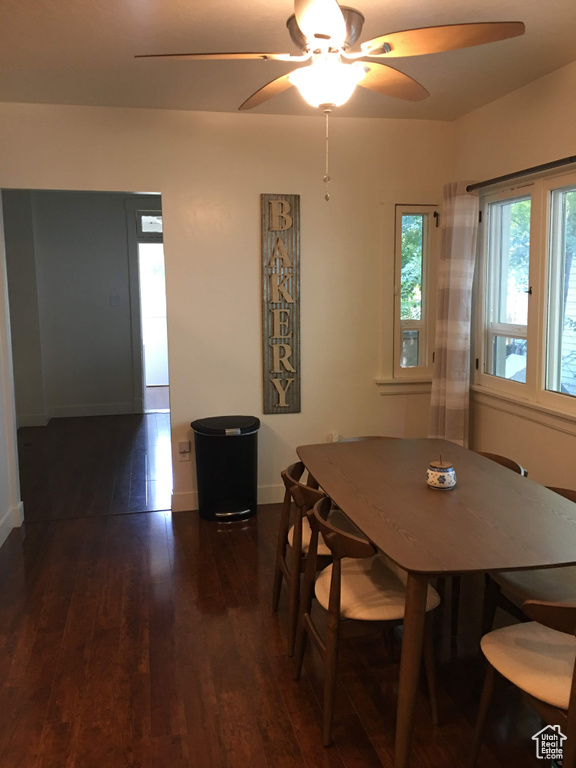 Dining space with dark wood-style floors, ceiling fan, and baseboards
