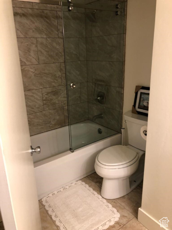 Bathroom with washtub / shower combination, toilet, and tile patterned flooring