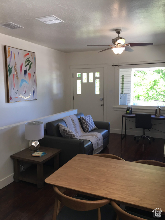 Living area with wood finished floors, baseboards, ceiling fan, and a textured ceiling