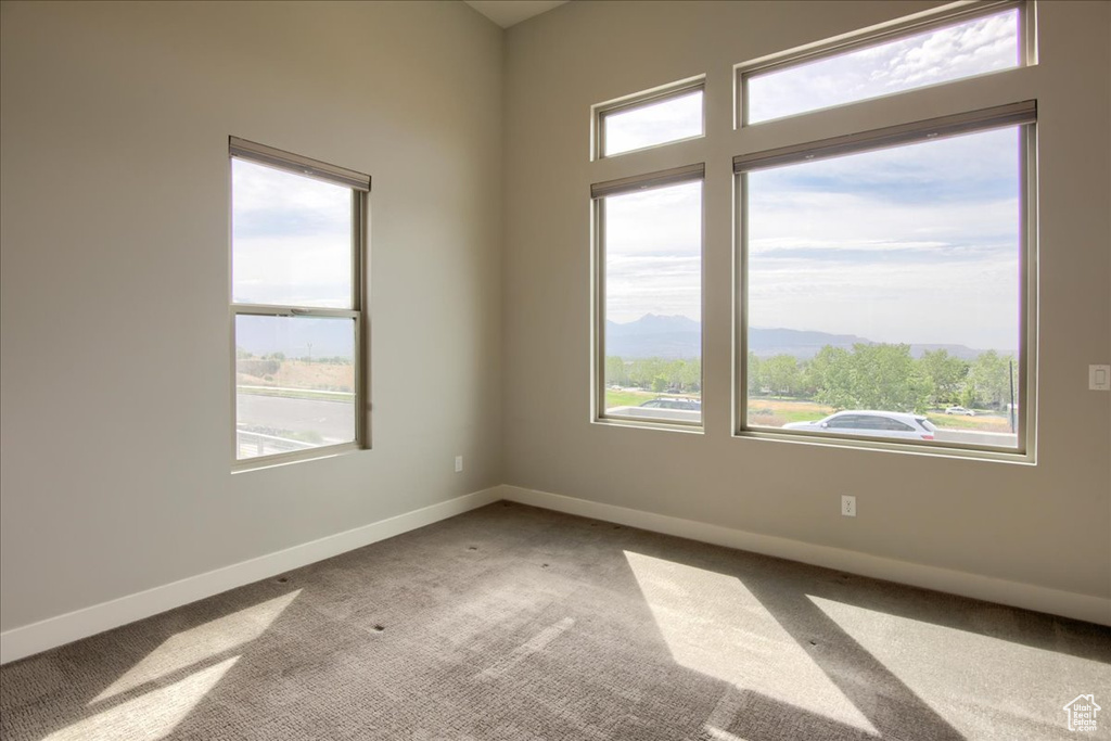 Carpeted empty room featuring plenty of natural light, baseboards, and a mountain view