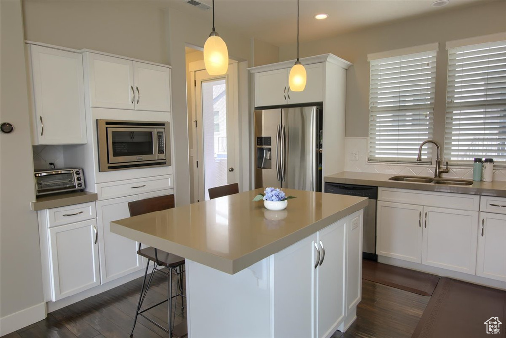 Kitchen with appliances with stainless steel finishes, a sink, white cabinets, a kitchen island, and recessed lighting