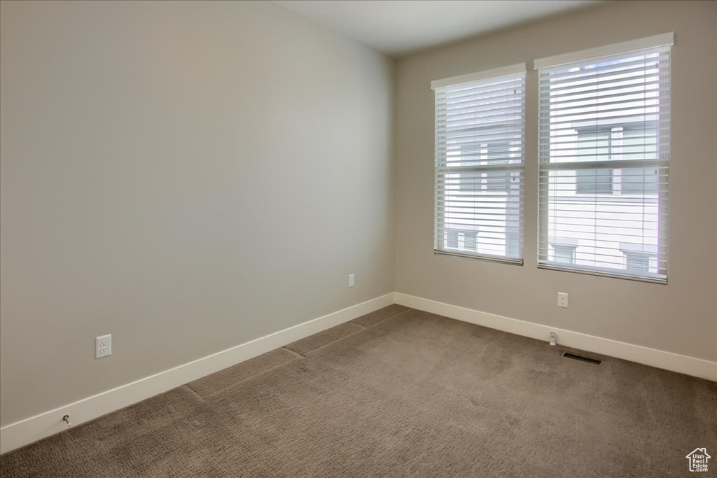 Unfurnished room featuring dark carpet and baseboards