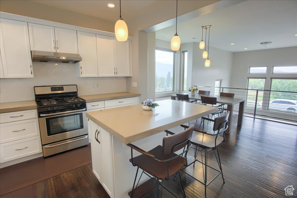 Kitchen with stainless steel range with gas cooktop, under cabinet range hood, white cabinets, tasteful backsplash, and recessed lighting