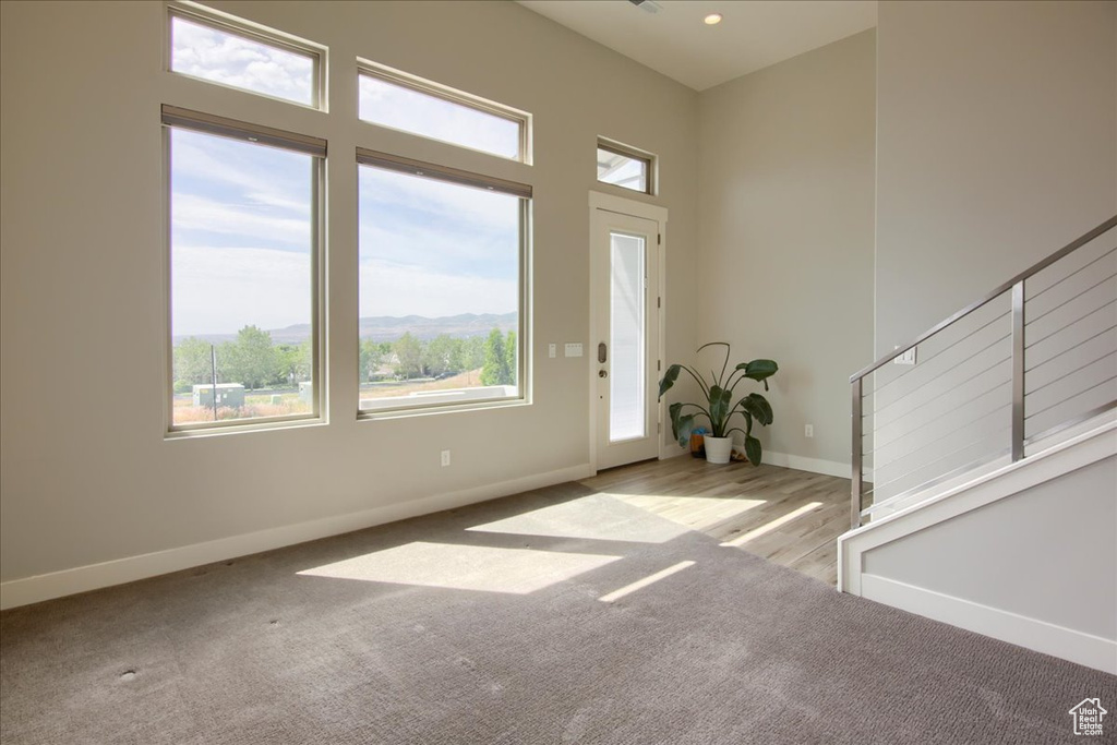 Carpeted foyer featuring healthy amount of natural light, stairs, baseboards, and a towering ceiling