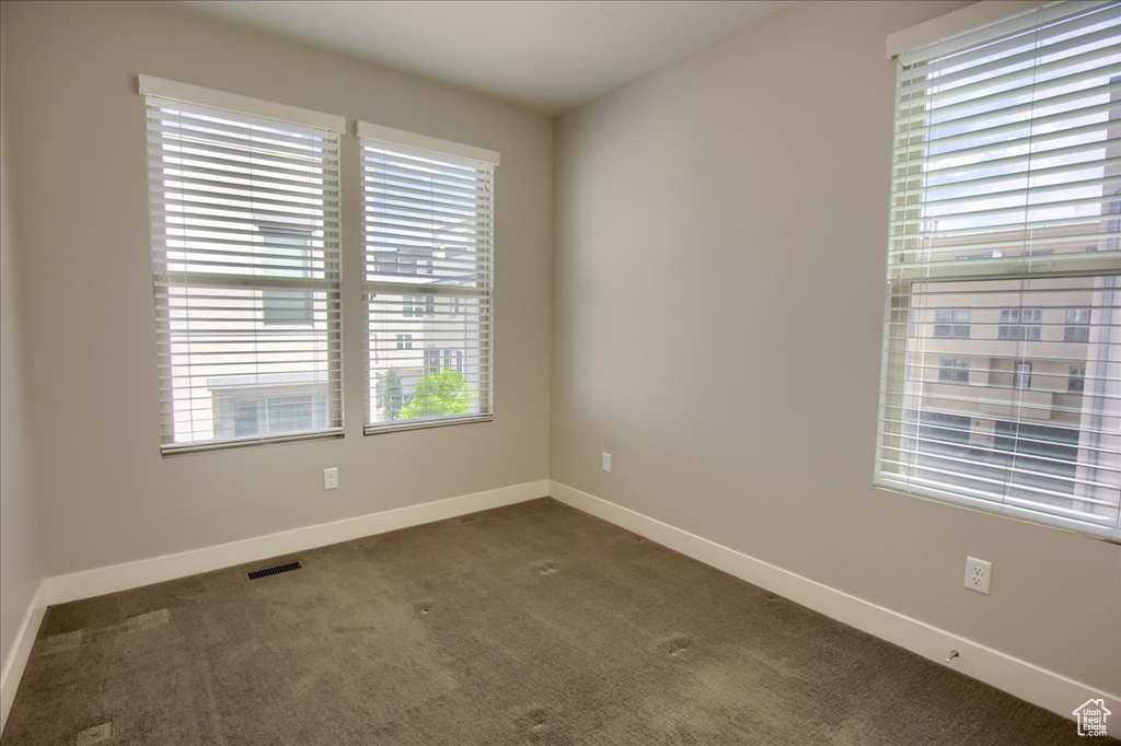 Unfurnished room featuring dark colored carpet and baseboards