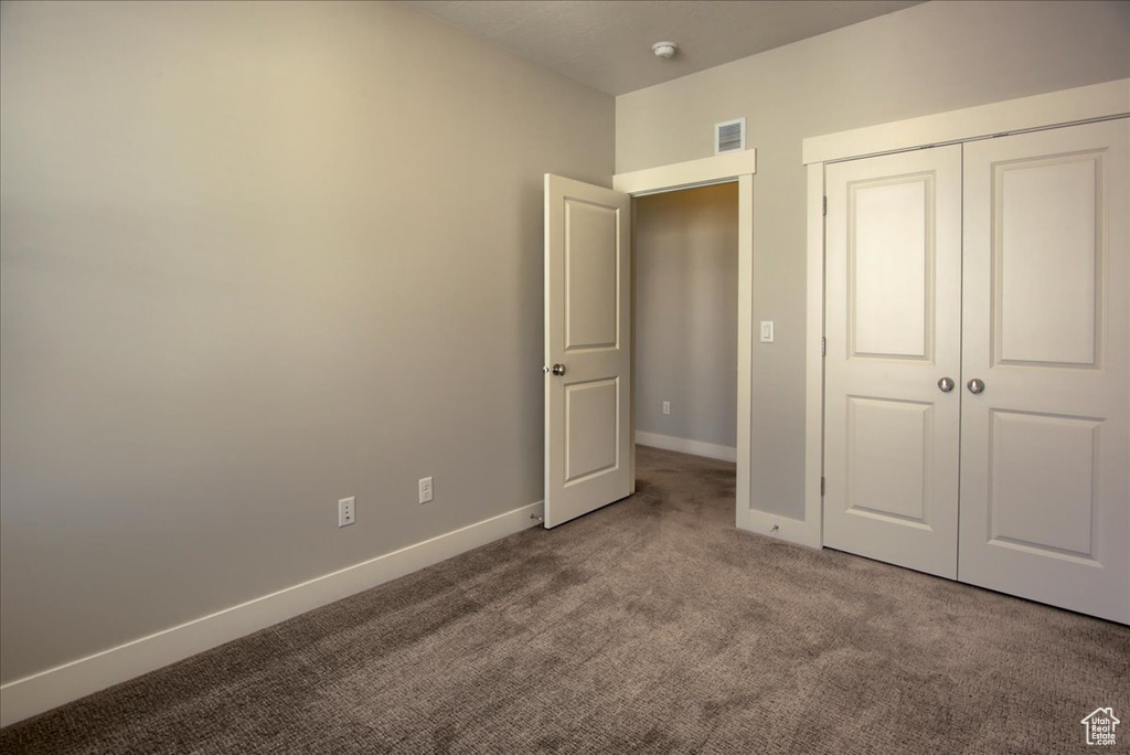 Unfurnished bedroom featuring carpet flooring, baseboards, and a closet