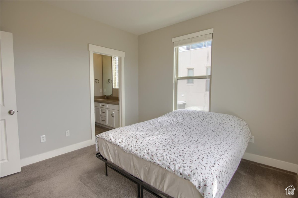 Bedroom featuring baseboards, dark colored carpet, and connected bathroom